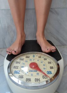 Image of a white persons bare feet on a large dial style bathroom scale